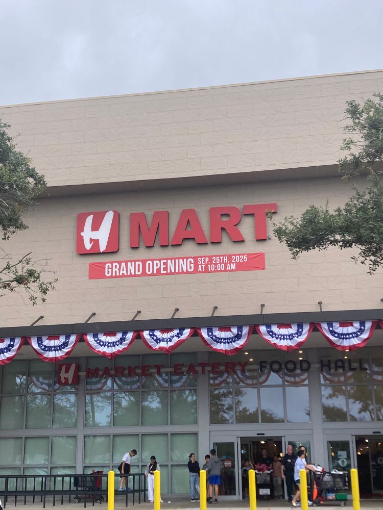 Storefront of H Mart, with red white & blue flag bunting on the front. There is a red sign that says “GRAND OPENING SEP. 25th 2025” at 10:00am” 