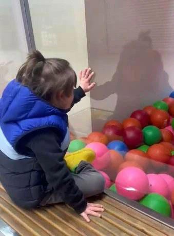 Bir top havuzunun camına dışarıdan elini dayamış içeri bakan, arkadan gördüğümüz şişme yelekli
ve saçının bir kısmı tepeden bir tokayla tutturulmuş bir erkek çocuğu.