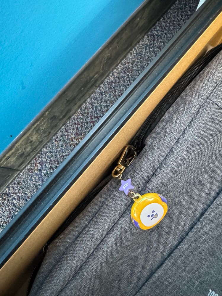 Grey fabric backpack with BT21 Chimmy charm in a desk drawer 