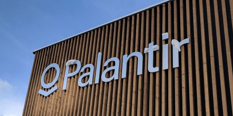 „Palantir pavilion, World Economic Forum, Davos, Switzerland“ von gruntzooki ist lizenziert unter CC BY-SA 2.0. Zu sehen ist ein holzverkleidetes Gebäude mit dem Logo von Palantir.