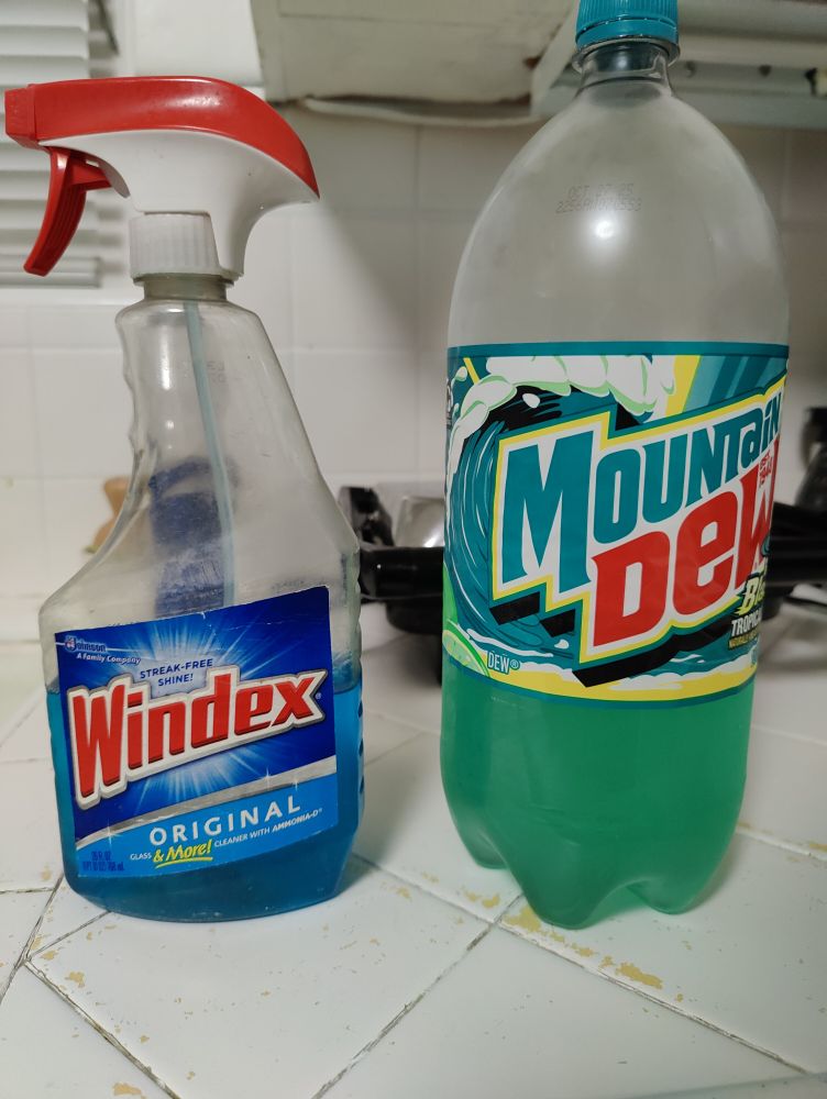 A bottle of mountain dew and a bottle of windex, placed suspiciously near each other