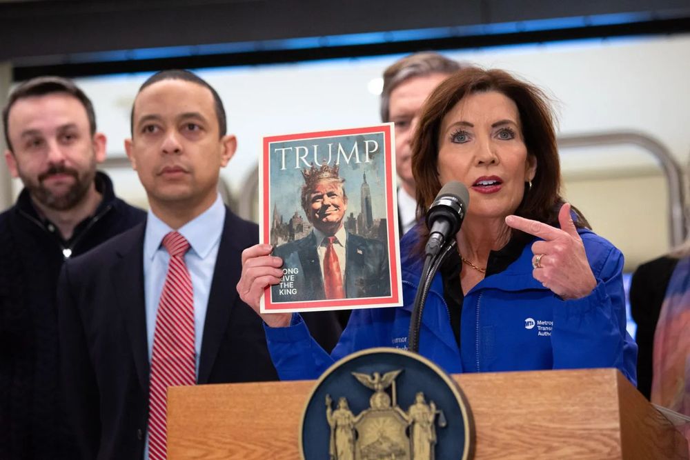 Gov. Kathy Hochul holds up a fake TIME Magazine cover photo of Pres. Donald Trump in which he's depicted as wearing a crown. 