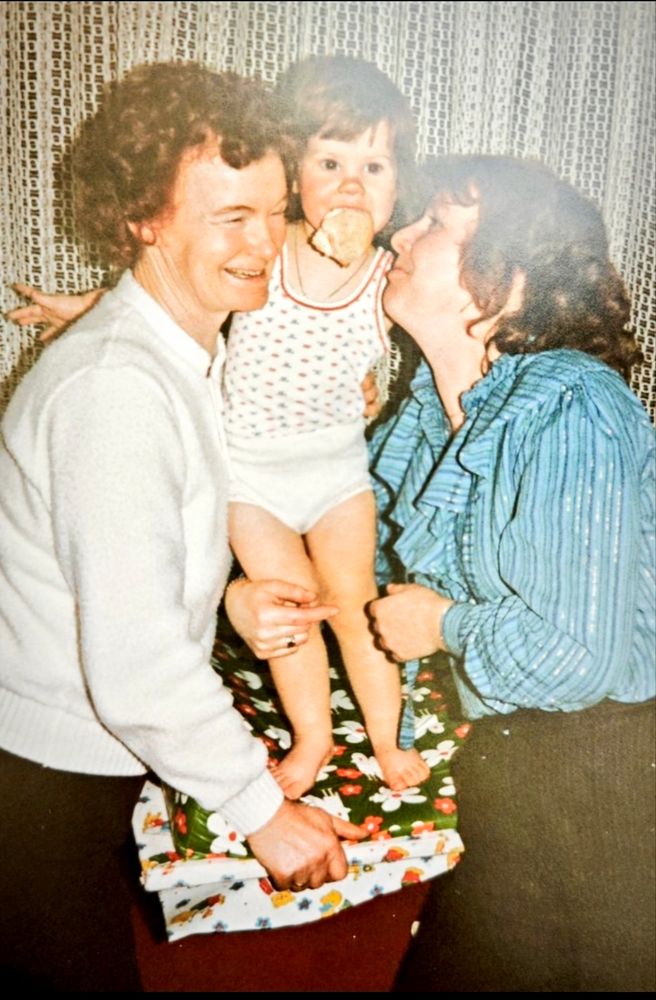 Auf dem Foto bin ich mit 2 Jahren und werde von meiner Oma und meiner Mama umarmt. 