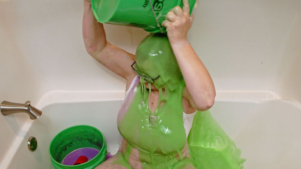 I'm sitting in a bathtub, dumping a bucket of green slime on my head