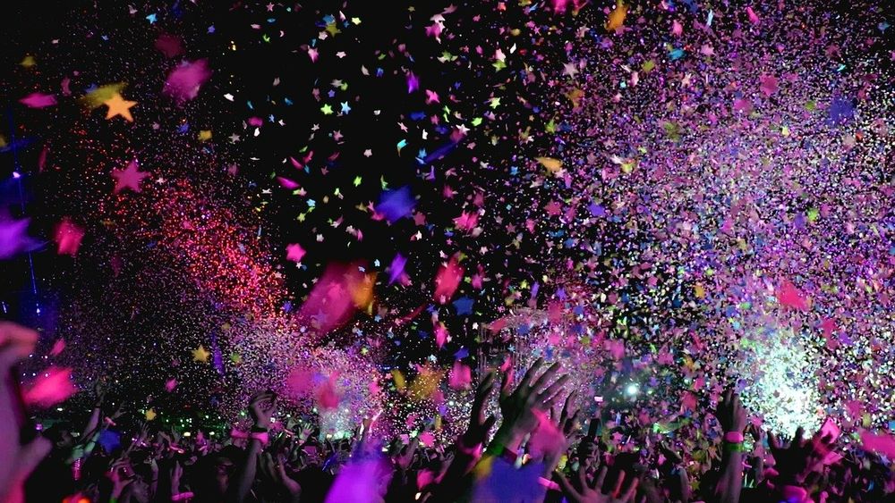 People at a night concert with confetti and ticker tape in the air.