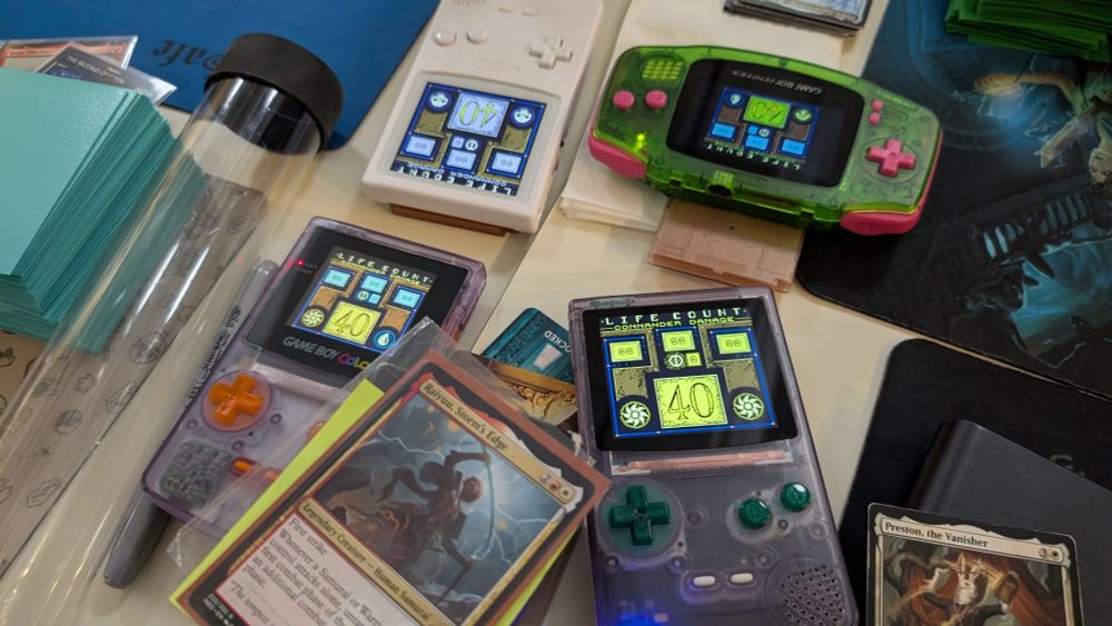 Game of Commander, Magic the Gathering trading card game where we're using two purple game boy colors, a white game boy and a green game boy advance for life counters. 