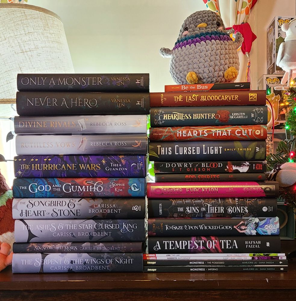 Two stacks of books placed next to each other, pigeon plushie on top of the right stack