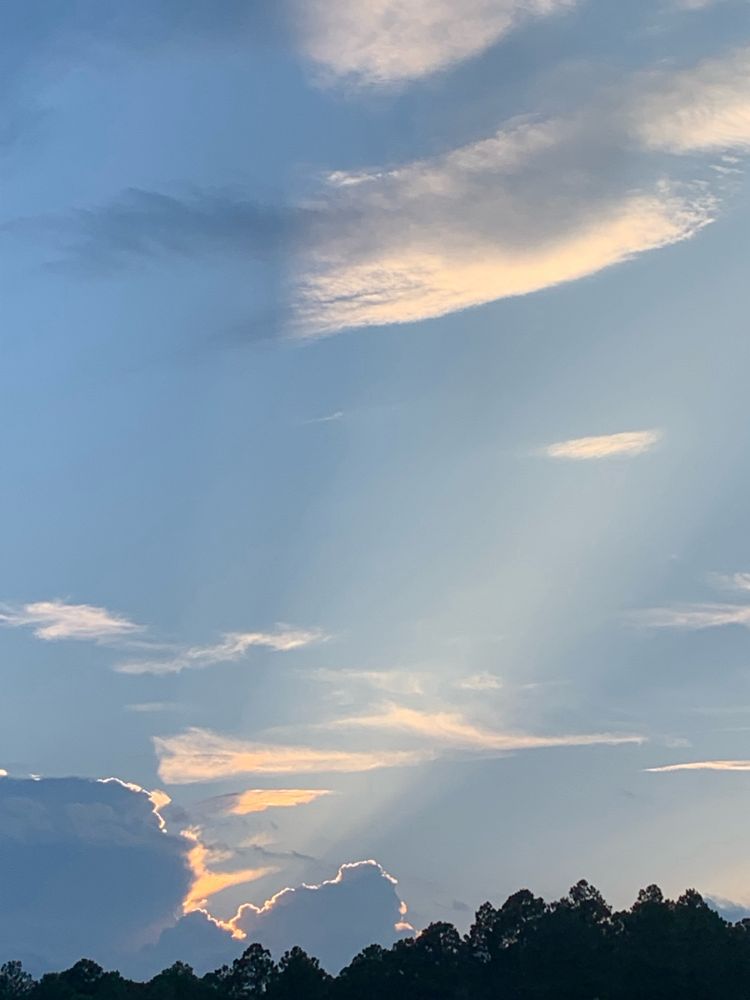 Sun shining through the clouds in a way such that it illuminates the sky in lines