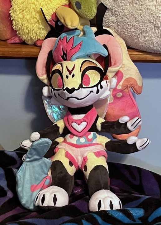 premium plushie of queen bee from helluva boss sitting on a fluffy blanket