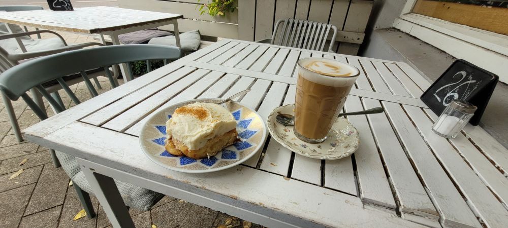 Ein Zimtschnecke und ein Latte Macchiato auf einem weißen Café Tisch. 