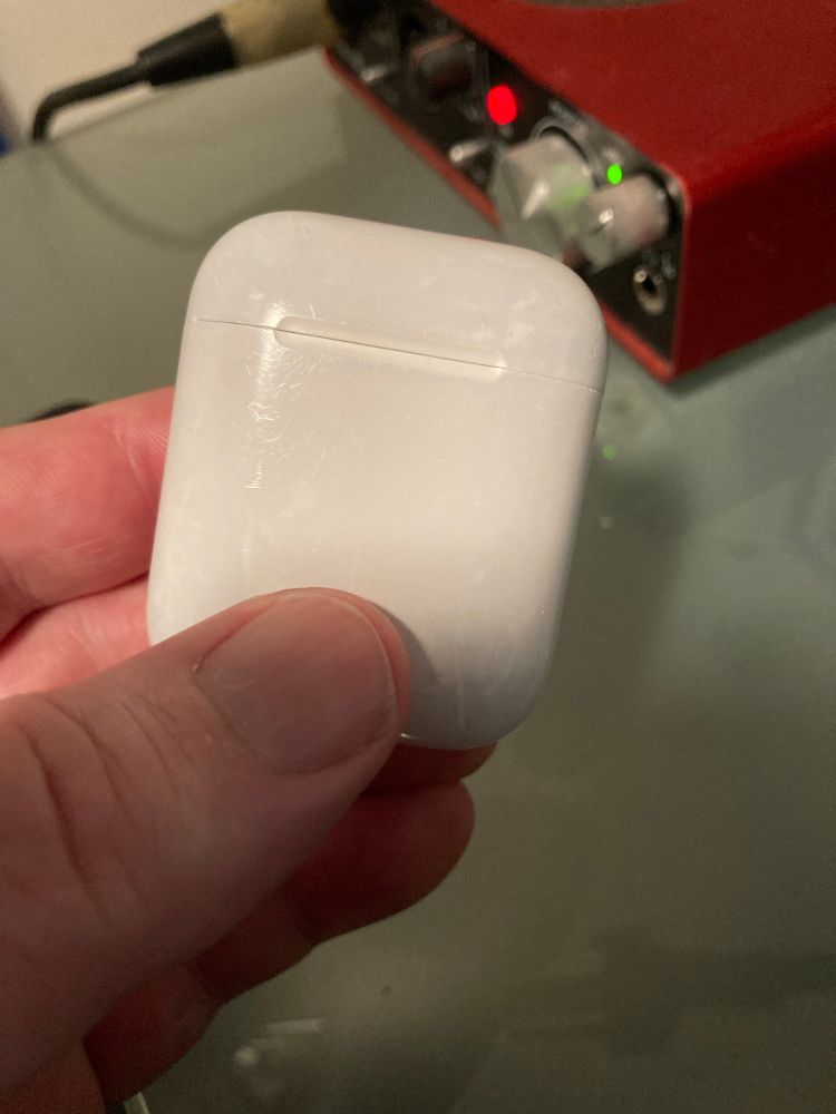 A hand holding an AirPods case.