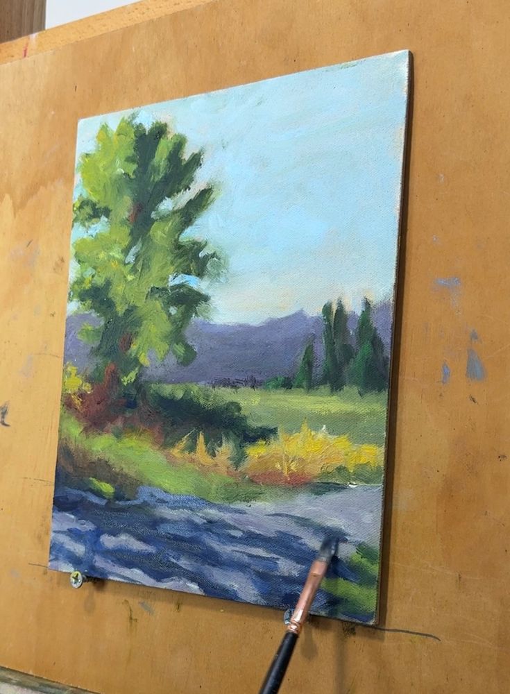 A plein air painting in progress featuring a tree in a rural scene with dappled shadows in the foreground 