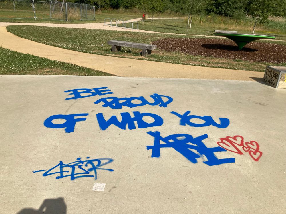 Blue graffiti that says: BE PROUD OF WHO YOU ARE ❤️