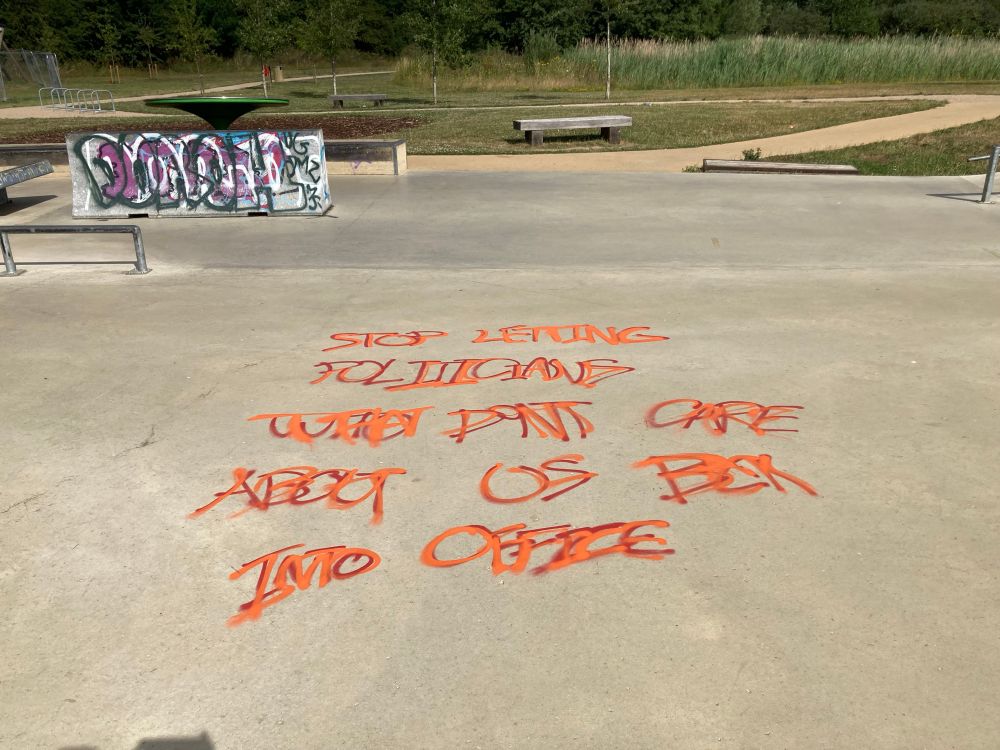 Orange graffiti that says: STOP LETTING POLITICIANS THAT DONT CARE ABOUT US BACK INTO OFFICE