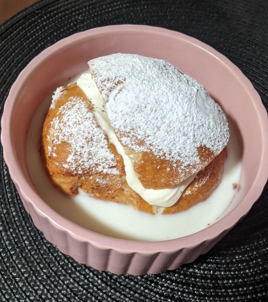Una semla (pan tradicional sueco relleno de pasta de almendras) en un tazón con leche.