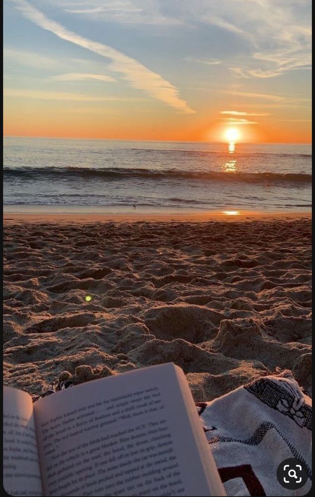 Sunset at a sandy beach. An open book in the foreground 