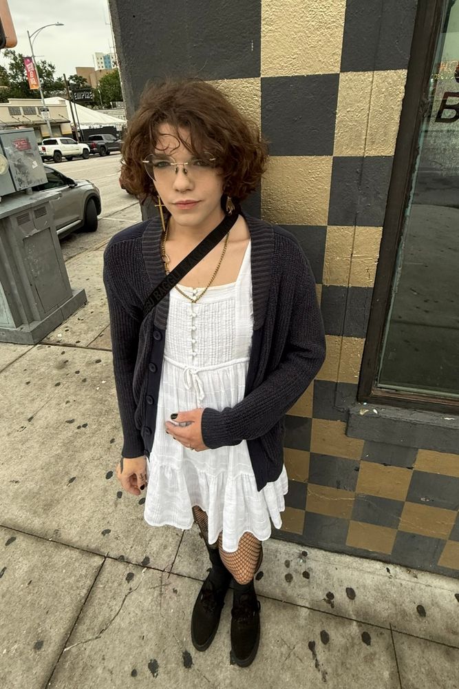 top down wide lens photo of a woman in a white dress and dark cardigan smoking a cigarette 