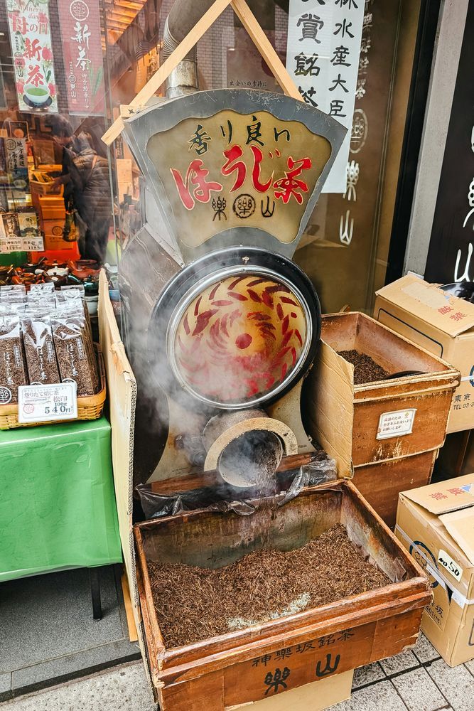 Traditional hojicha roasting machine with circular rotating drum displaying tea leaves being roasted at a Japanese tea shop.
