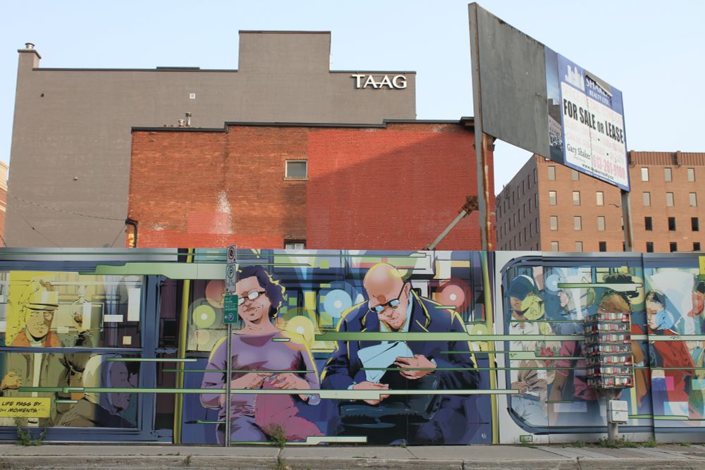 A photo of a mural in front of some buildings in Centertown, the mural looks like people on a moving train