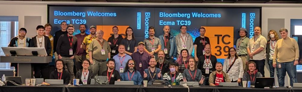~35 TC39 delegates on the stage in front of a sign that says "Bloomberg Welcomes Ecma TC39"