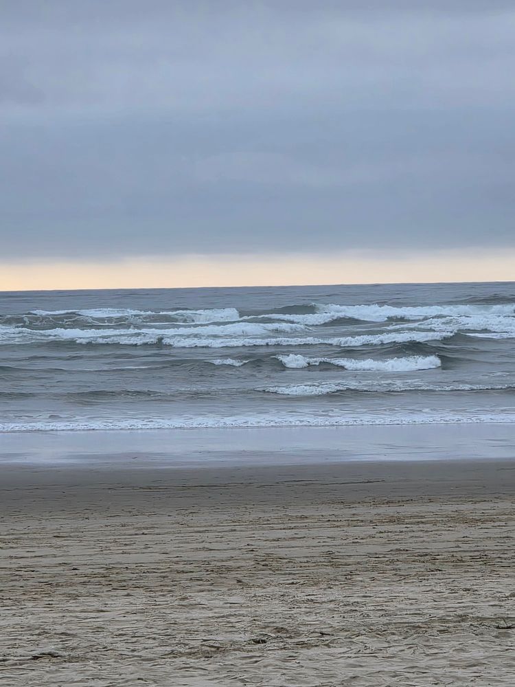 View of Pacific Ocean waves lapping the beach early on an overcast morning in Seaside, Oregon.