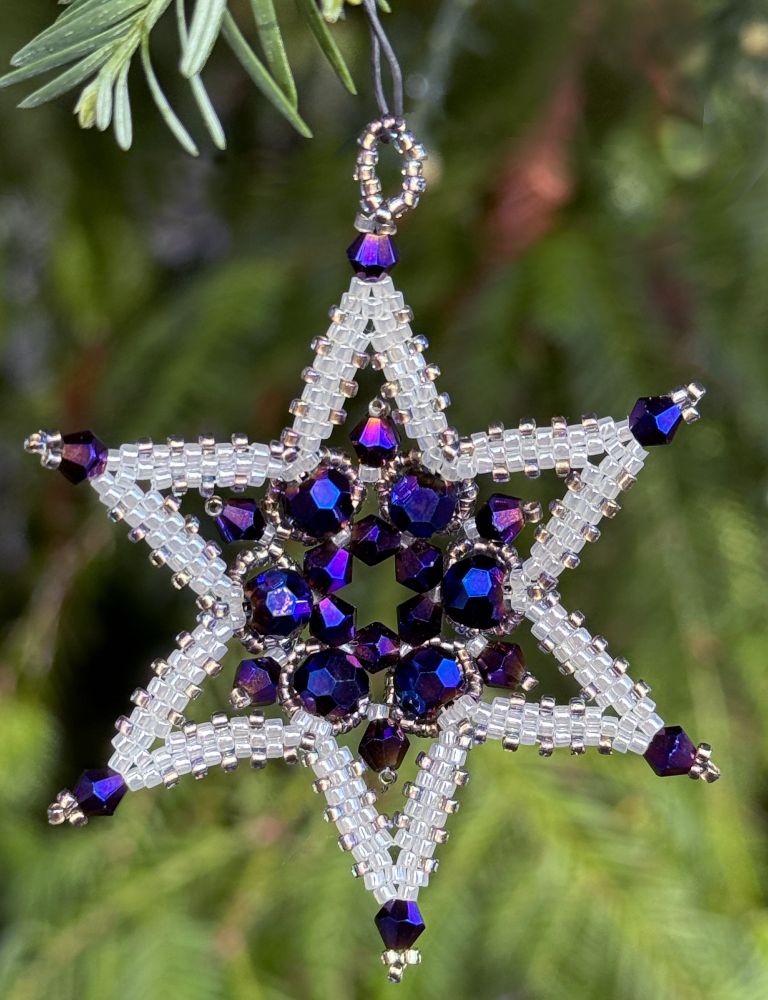 White beaded star ornament with purple crystals.
