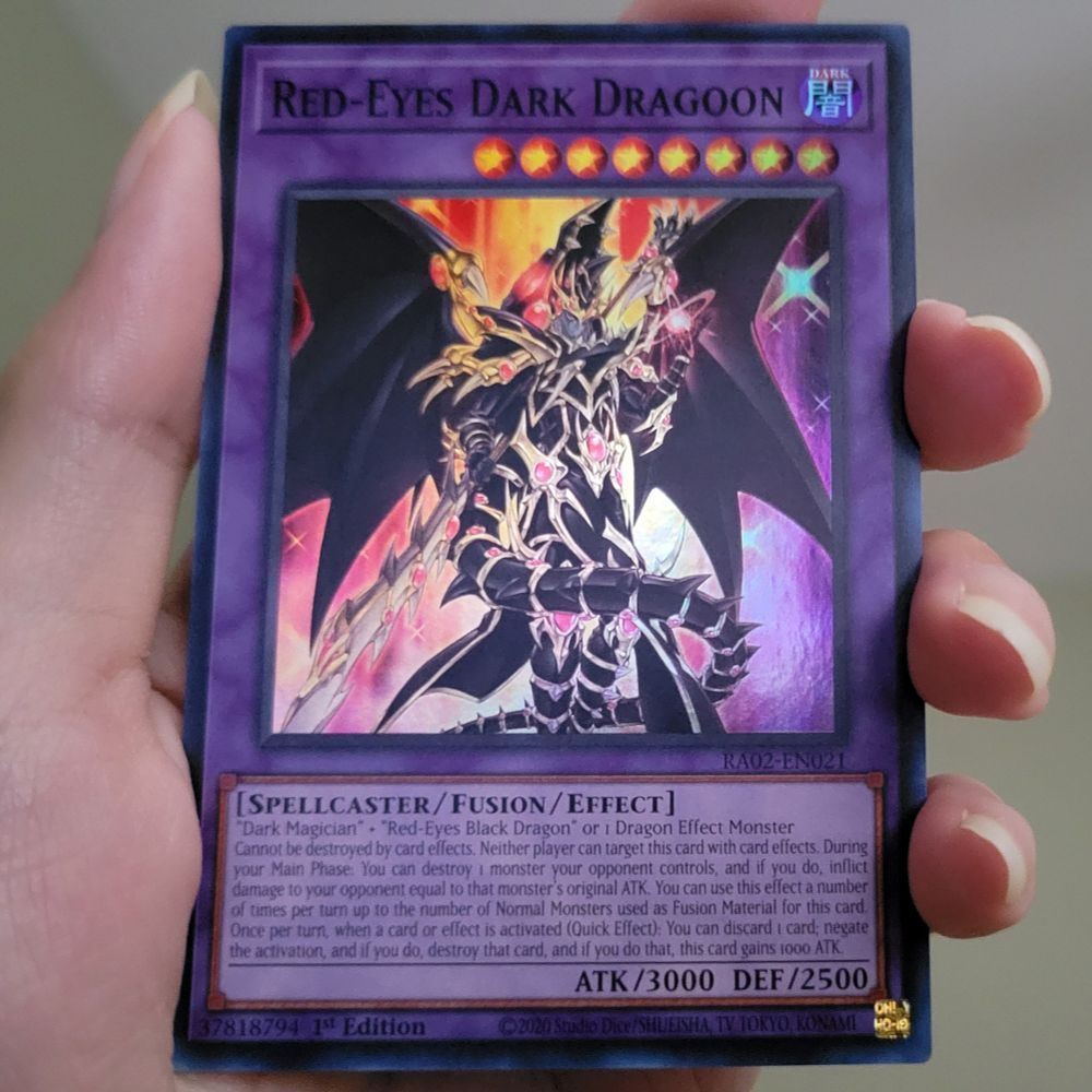 Psycho Pretzel's hand holding the Yu-Gi-Oh card Red-Eyes Dark Dragoon