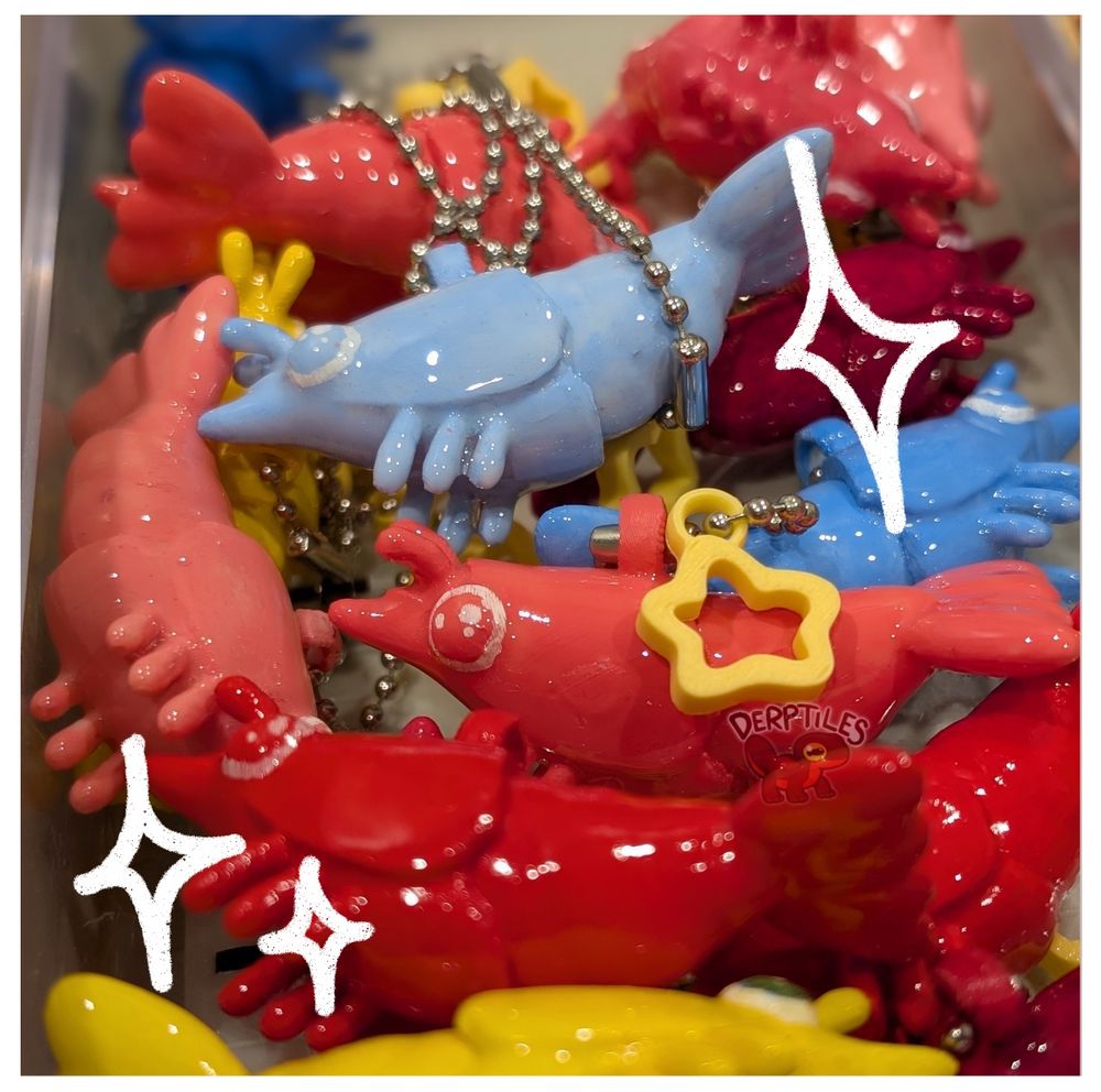 A photo of an assortment of brightly colored, shiny, homemade shrimp figurines in a pile with sparkles drawn over them