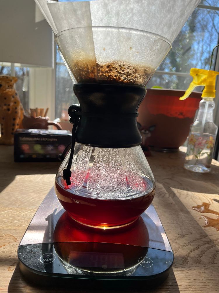 Sun lighting up an hourglass shaped glass chemex coffee maker