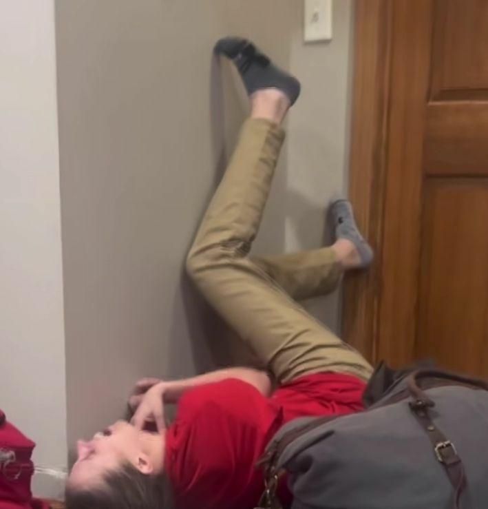 A woman who's fallen on the floor with her legs in the air, crying out in pain