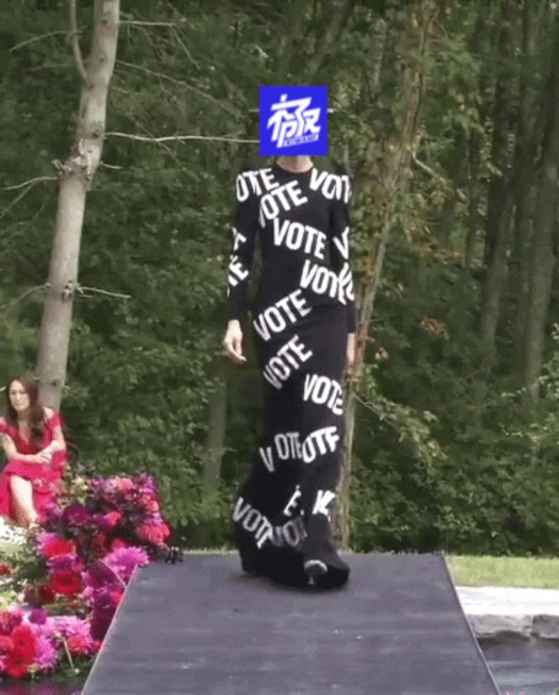 a model walks down a runway wearing a black dress that says vote