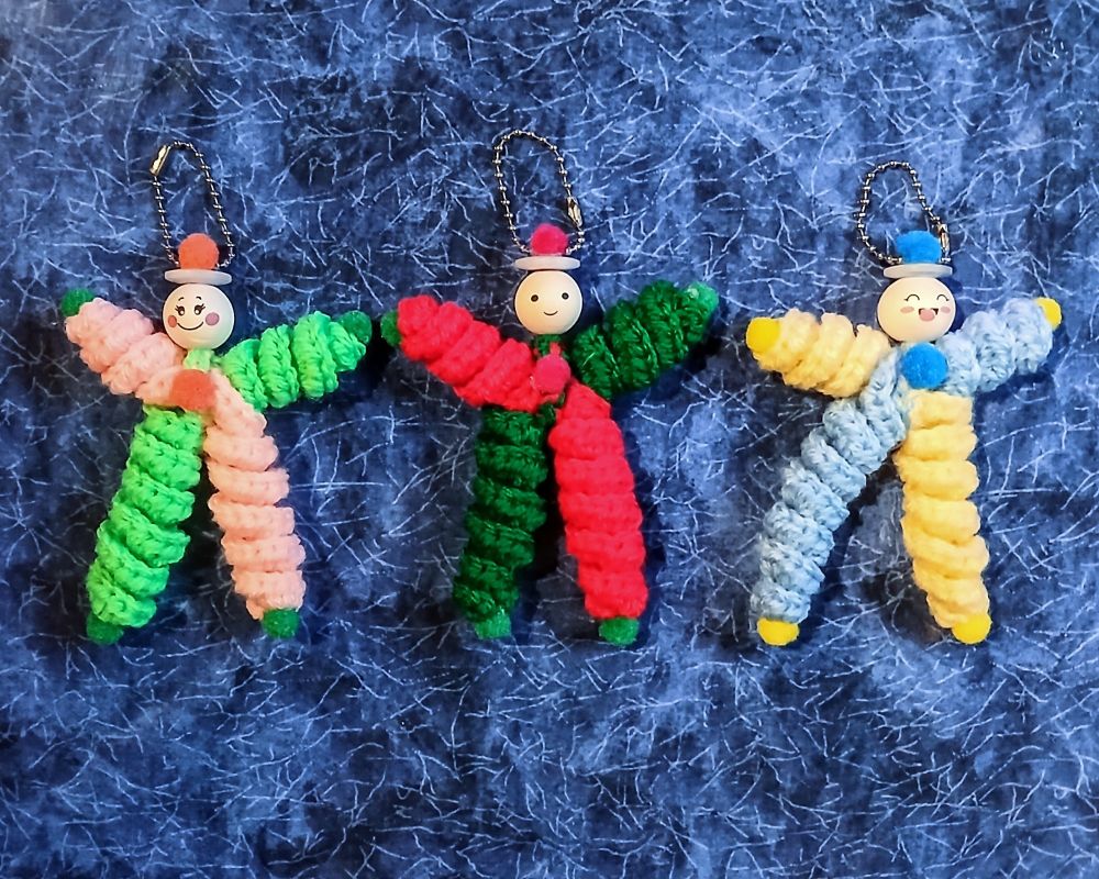Three bright coloured crocheted dolls with wooden bead heads and button hats