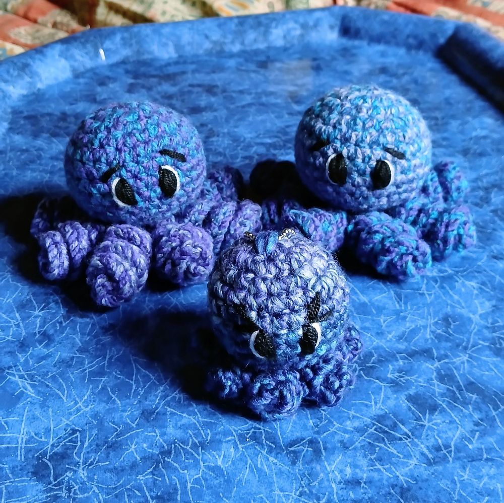 Three small blue crocheted octopi
