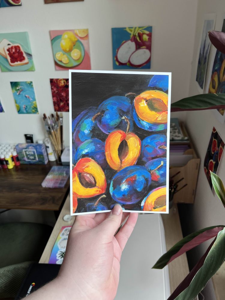 A photo of me holding a print of my "Atutmn Plums" painting.