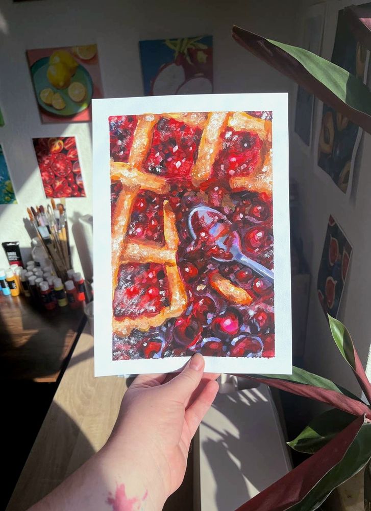 Me holding my cherry pie painting, beautifully lighting up in a beam of light.