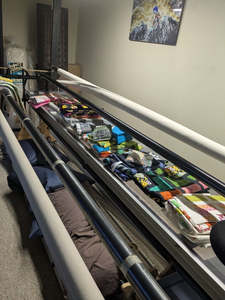 A row of colorful piles if quilt components lined up on a longarm table. 