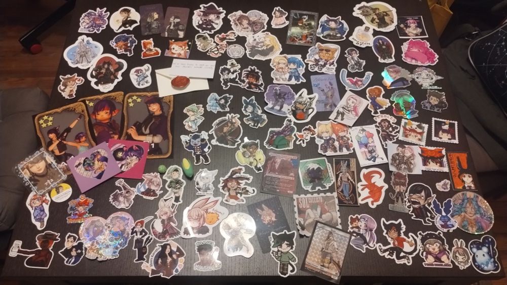 A large number of stickers featuring art of the WoLs of multiple players laid out on a table.