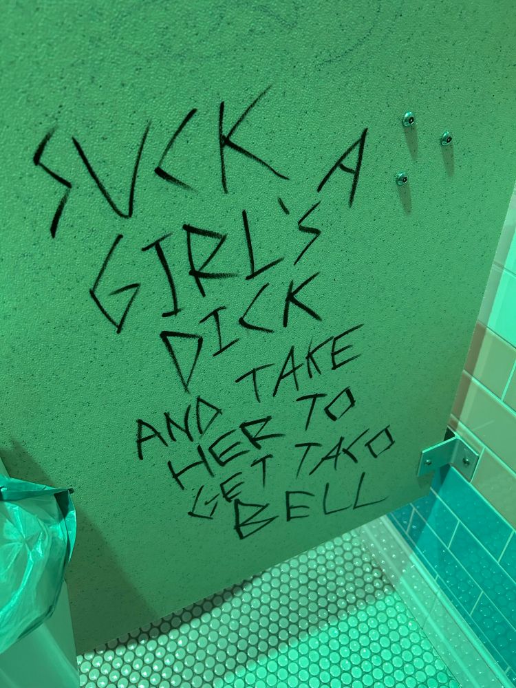 Bathroom stall graffiti reading “suck a girl’s dick and take her to taco bell”