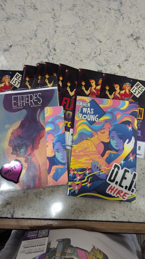 Two comics (Etheres, and When I was Young) two stickers (one reads DEI hire and the other reads Shitty Fan Fic) and a book mark featuring the cover of When I was Young.