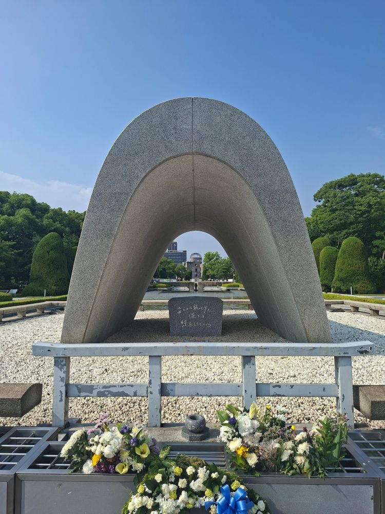 Photo du cénotaphe du parc de la paix. En arrière-plan on peut apercevoir la flamme de la paix et le dôme de Genbaku