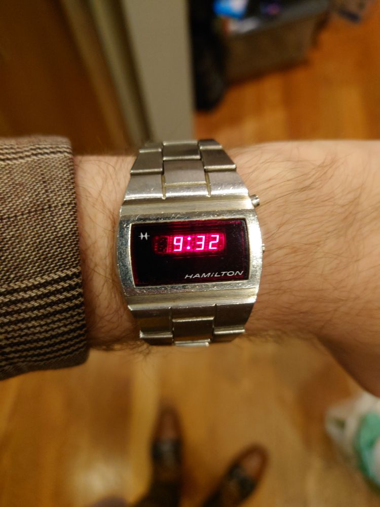 A silver digital watch with a red LED display.