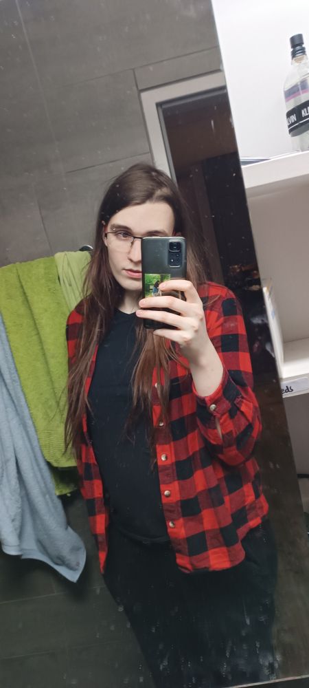 white woman in red plaid top, black pants and undershirt, with long dark brown hair