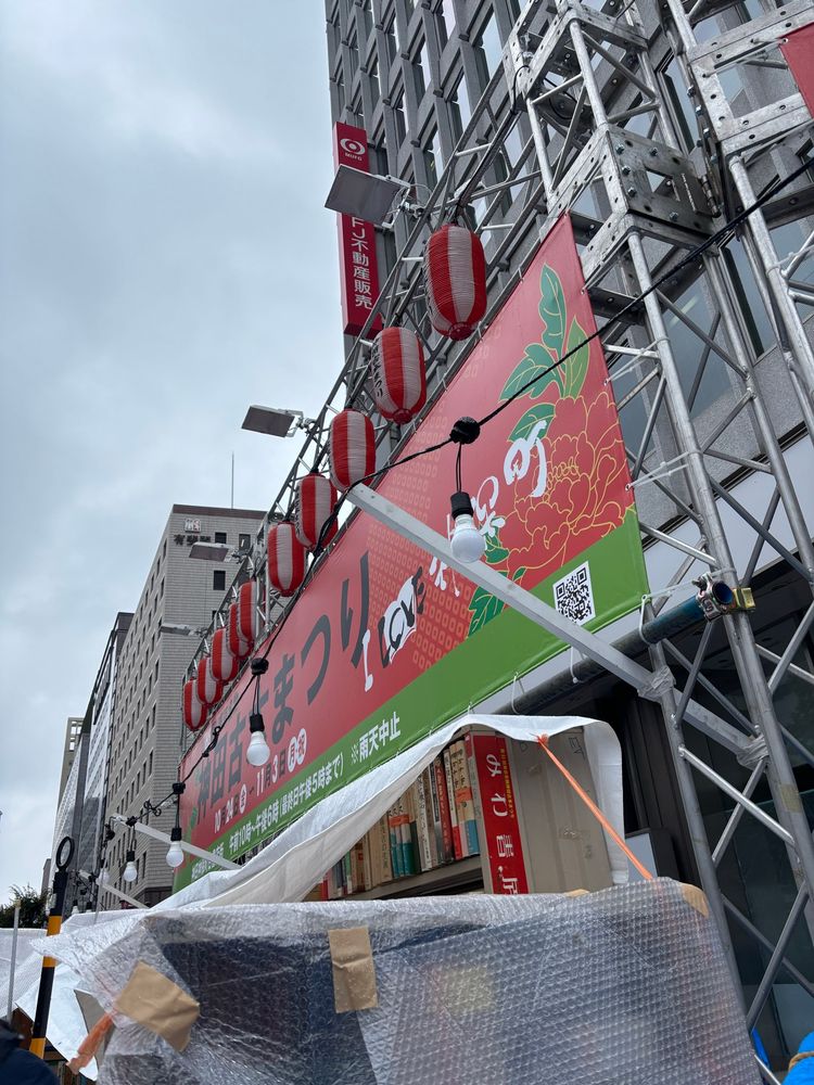 神田古本まつりの看板。
赤い牡丹が描かれた背景の上に黒い文字で、神田古本まつりと書かれている。