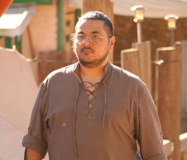 Demantic wearing a medieval style grey shirt walking 