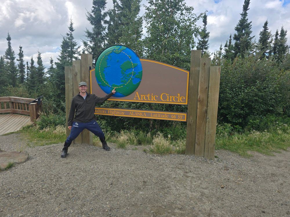 A student poses in front an Arctic Circle sign on the Dalton Highway