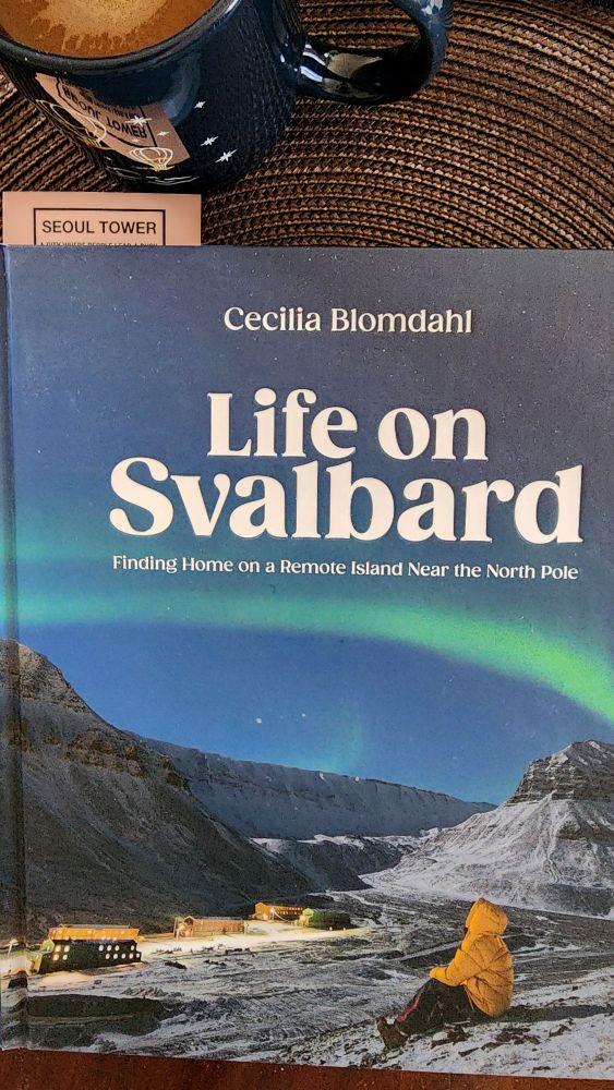 Cup of coffee and a copy of the book Life on Svalbard by Cecilia Blomdahl, a Swedish YouTuber who cares what it's like living on the Norwegian island of Svalbard up near the north pole