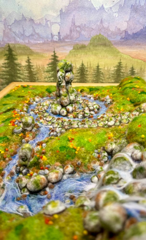 A 3D needle felted landscape with a standing stone, river and waterfall
