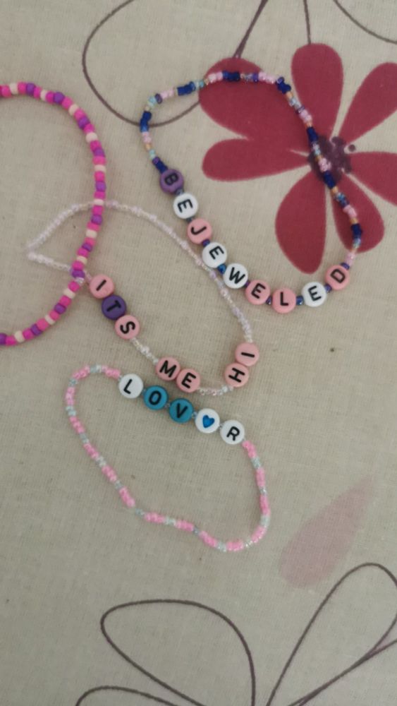 Freundschaftsarmbänder, links in rosa oben "Bejeweled", in der Mitte "It's me, hi" und unten "Lover"