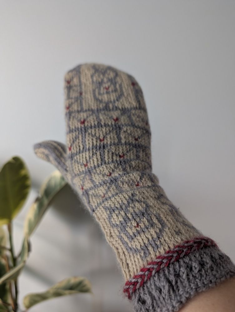 Photo is showing the back of a right-handed mitten. 

Harry Potter inspired mittens. Mittens are covered in knitted letters and owls in a cream background, with gray outlines, and red accents. 

Yarn is Kambgarn