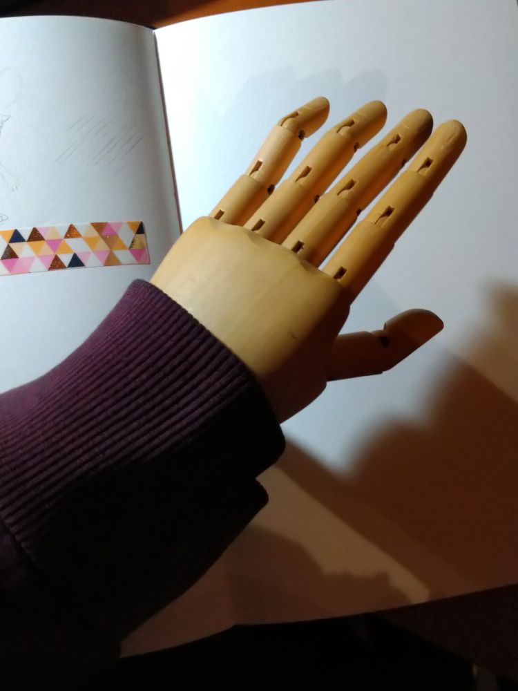 It's a photo of a wooden hand model instead of the person's real hand. This is supposed to be a joke.